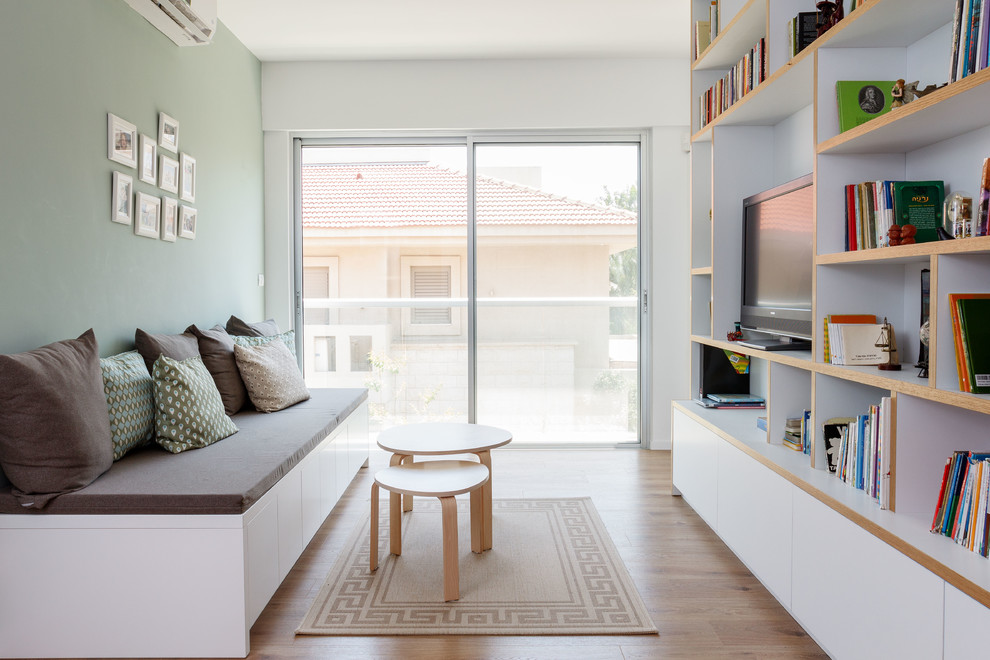 Imagen de sala de estar con biblioteca cerrada contemporánea con paredes blancas, suelo de madera clara, televisor independiente y suelo beige