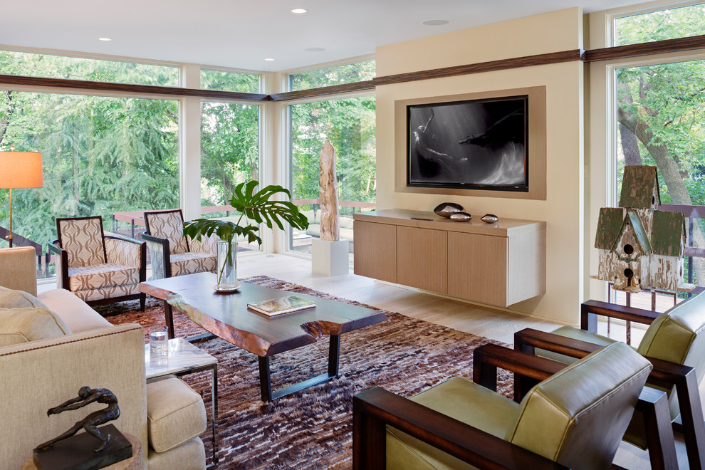 Diseño de sala de estar actual con paredes beige, suelo de madera clara y televisor colgado en la pared