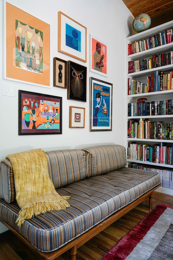 Immagine di un soggiorno moderno di medie dimensioni con libreria, pareti bianche, pavimento in legno massello medio e tappeto