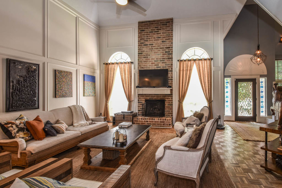 Großes, Offenes Klassisches Wohnzimmer mit grauer Wandfarbe, braunem Holzboden, Kamin, Kaminumrandung aus Backstein und TV-Wand in Houston