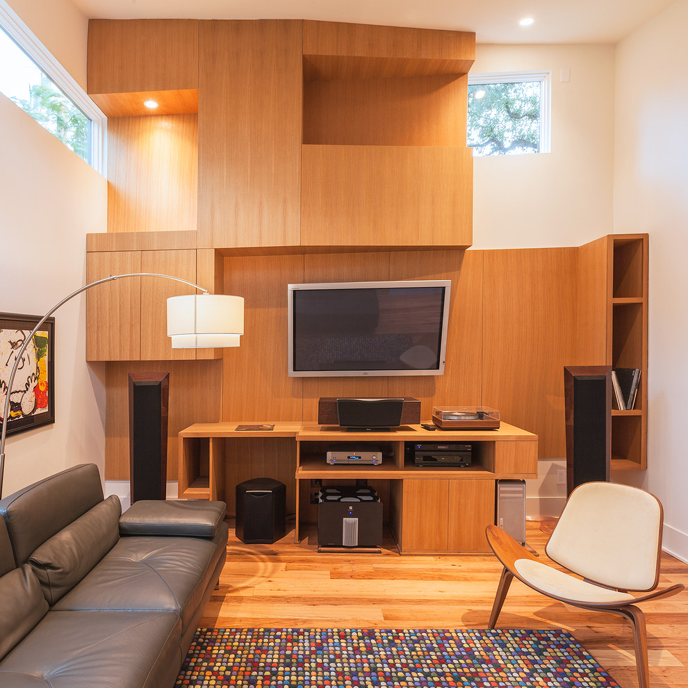 На фото: изолированная гостиная комната среднего размера в современном стиле с бежевыми стенами, паркетным полом среднего тона и телевизором на стене