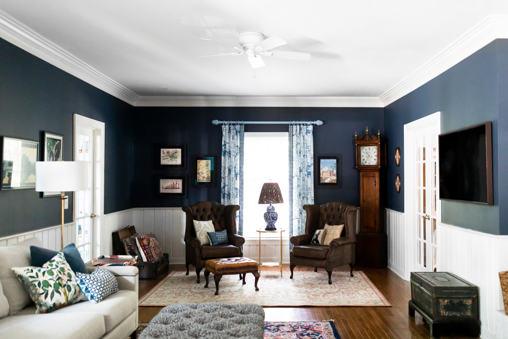Diseño de sala de estar cerrada tradicional grande con paredes azules, suelo de madera en tonos medios, marco de chimenea de ladrillo, televisor colgado en la pared y panelado