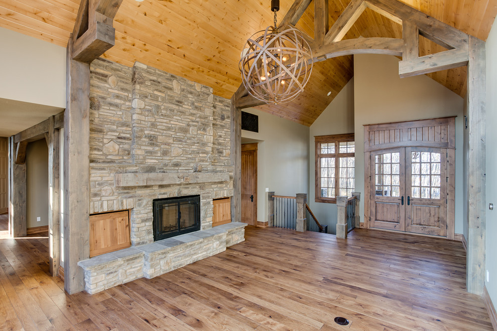 Large rustic open plan games room in Other with beige walls, medium hardwood flooring, a standard fireplace and a stone fireplace surround.