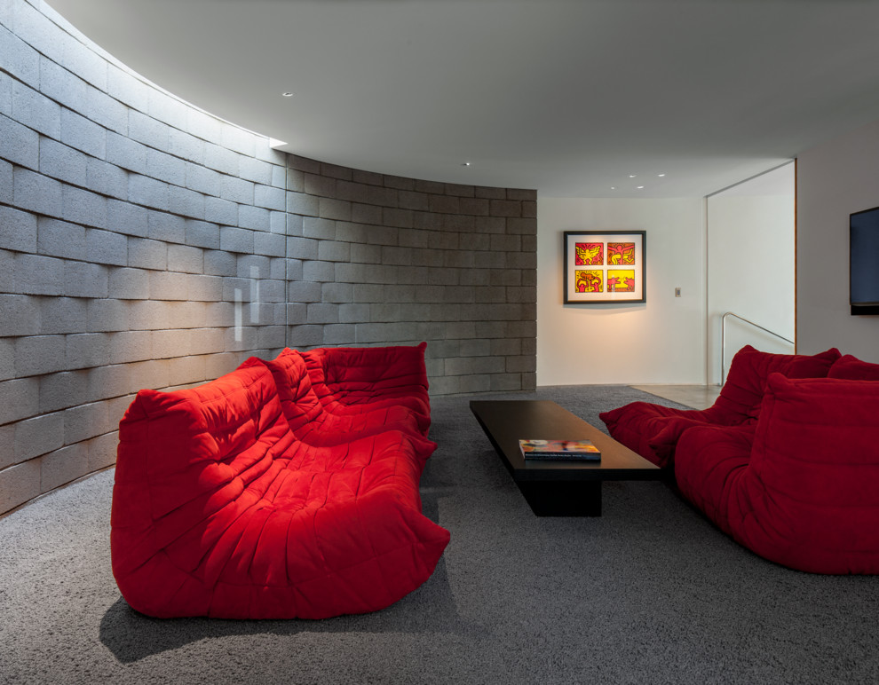 Стильный дизайн: большая открытая гостиная комната в стиле ретро с серыми стенами, бетонным полом, телевизором на стене и серым полом - последний тренд
