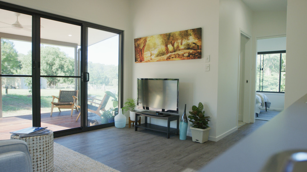 Kleines, Offenes Modernes Wohnzimmer mit weißer Wandfarbe, Vinylboden, freistehendem TV und grauem Boden in Sunshine Coast