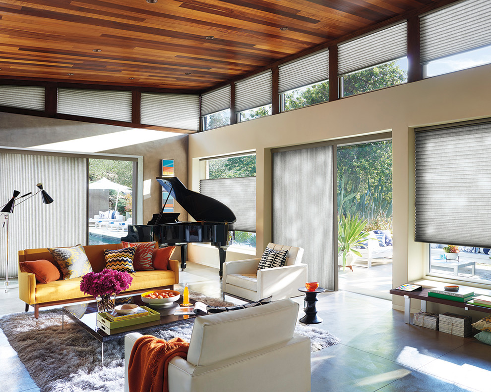 Medium sized contemporary open plan living room in New York with a music area, no tv, beige walls, concrete flooring, no fireplace, grey floors and feature lighting.