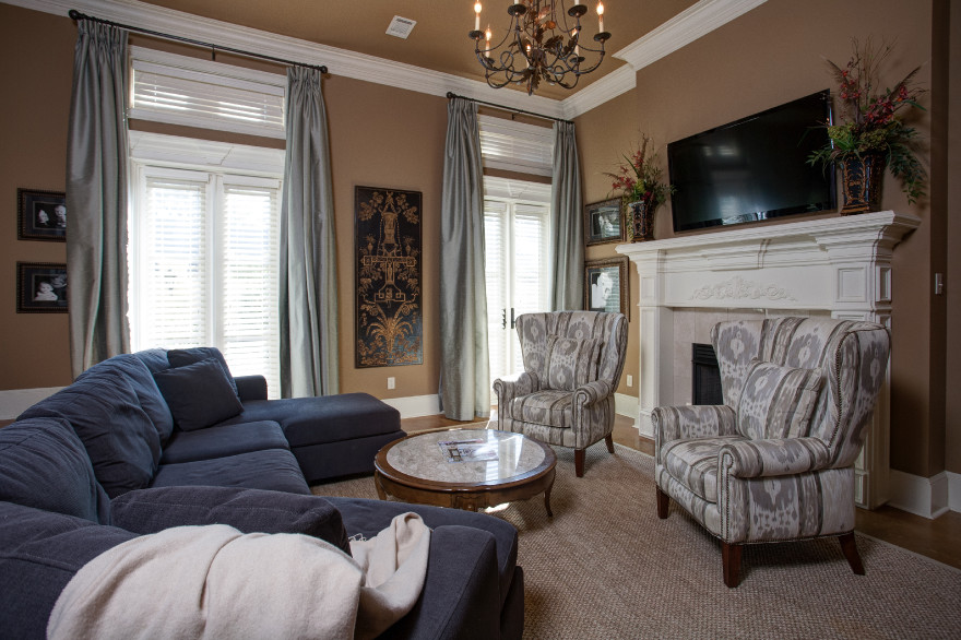 На фото: открытая гостиная комната среднего размера в классическом стиле с коричневыми стенами, темным паркетным полом, стандартным камином, фасадом камина из плитки, телевизором на стене и коричневым полом с