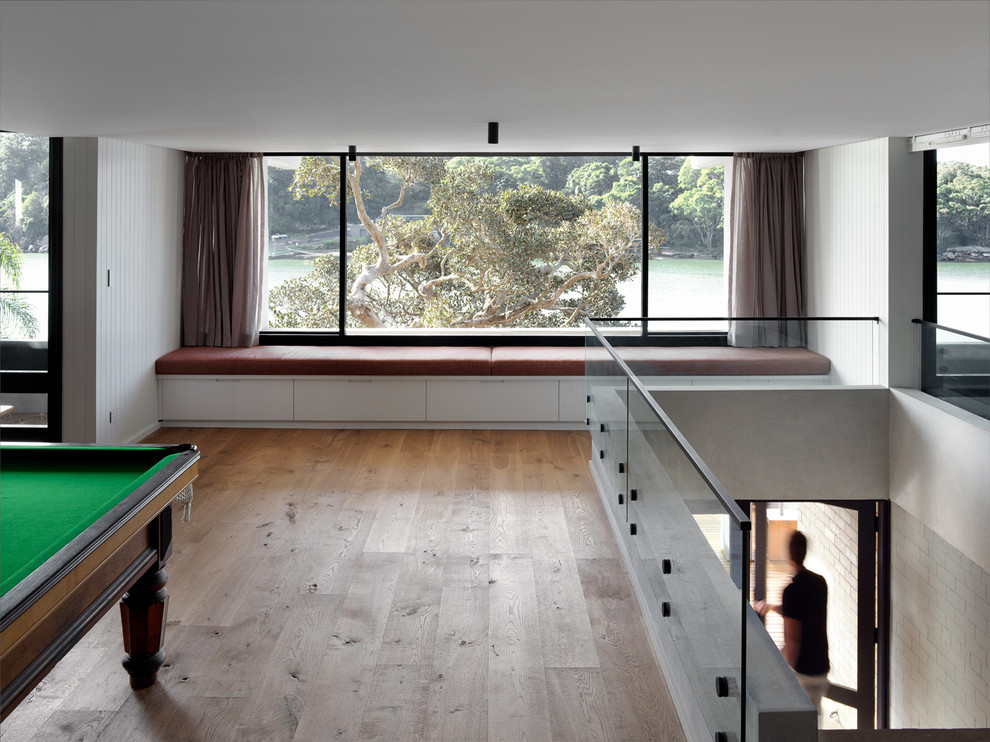Immagine di un ampio soggiorno minimalista aperto con sala giochi, pareti bianche, parquet chiaro e pavimento marrone