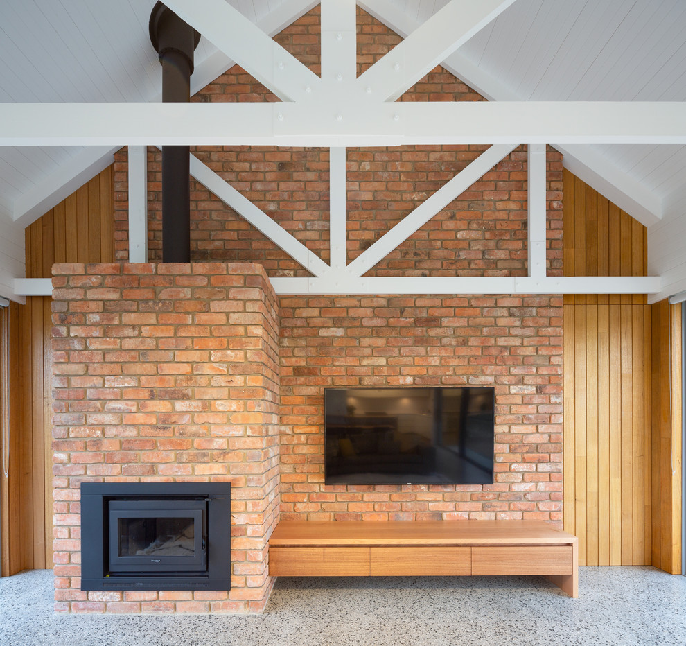 Exemple d'une salle de séjour nature de taille moyenne et ouverte avec un mur beige, sol en béton ciré, une cheminée standard, un manteau de cheminée en métal, un téléviseur fixé au mur et un sol gris.