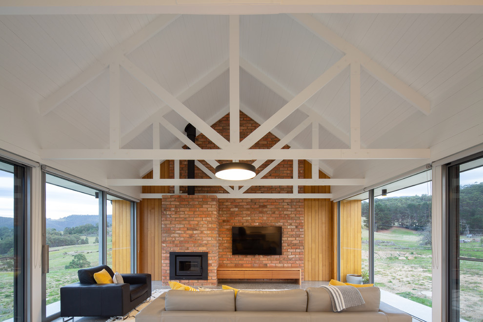 Exemple d'une salle de séjour nature de taille moyenne et ouverte avec sol en béton ciré, une cheminée standard, un manteau de cheminée en métal, un téléviseur fixé au mur et un sol gris.