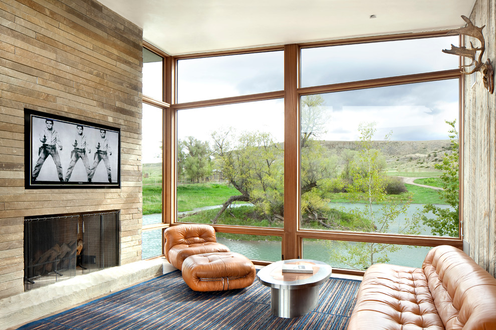 На фото: открытая гостиная комната в стиле модернизм с стандартным камином, фасадом камина из камня и телевизором на стене с