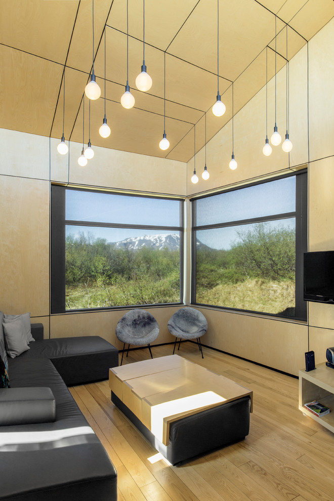 Ejemplo de sala de estar minimalista con suelo de madera clara, televisor colgado en la pared y suelo beige