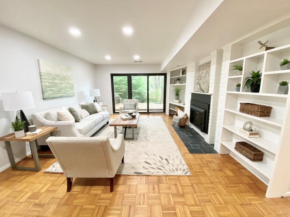 Esempio di un piccolo soggiorno chic chiuso con libreria, pareti grigie, pavimento in legno massello medio, camino classico e pavimento marrone