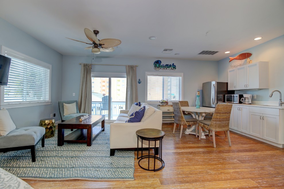 Пример оригинального дизайна: открытая гостиная комната среднего размера в морском стиле с синими стенами, полом из бамбука и телевизором на стене без камина