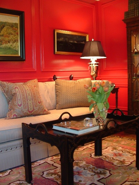 Cette photo montre une salle de séjour chic de taille moyenne et fermée avec une bibliothèque ou un coin lecture, un mur rouge et un sol en bois brun.