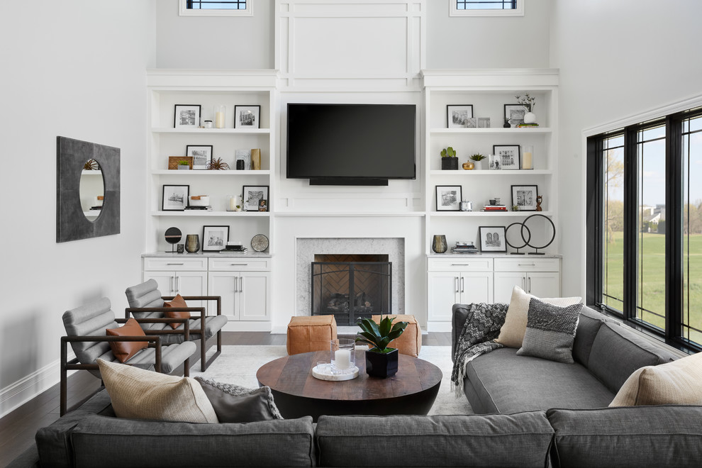 Источник вдохновения для домашнего уюта: гостиная комната в стиле неоклассика (современная классика) с серыми стенами, темным паркетным полом, стандартным камином, фасадом камина из камня, телевизором на стене и ковром на полу