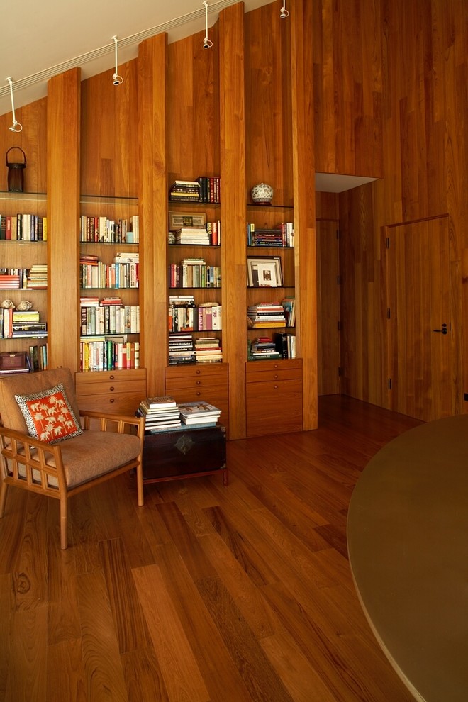 Modelo de sala de estar con biblioteca tropical con suelo de madera oscura