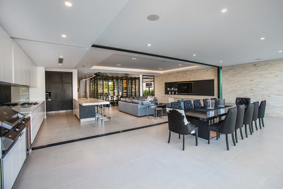 Modernes Wohnzimmer mit beiger Wandfarbe, Porzellan-Bodenfliesen, Kaminumrandung aus Stein und TV-Wand in Gold Coast - Tweed