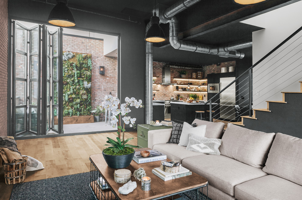 Esempio di un grande soggiorno industriale aperto con pareti nere, pavimento in legno massello medio e pavimento beige