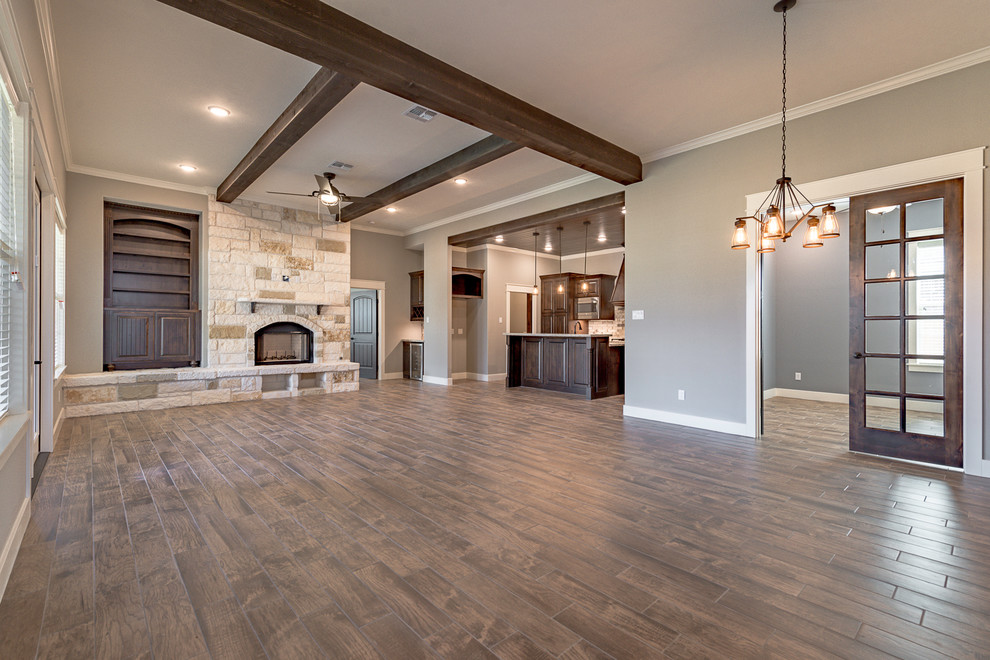 Example of a large urban open concept brown floor family room design in Other with a bar, a standard fireplace, a stone fireplace and a wall-mounted tv