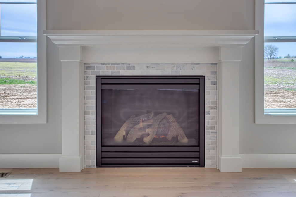 シカゴにあるお手頃価格の中くらいなカントリー風のおしゃれなオープンリビング (グレーの壁、淡色無垢フローリング、標準型暖炉、石材の暖炉まわり、ベージュの床) の写真