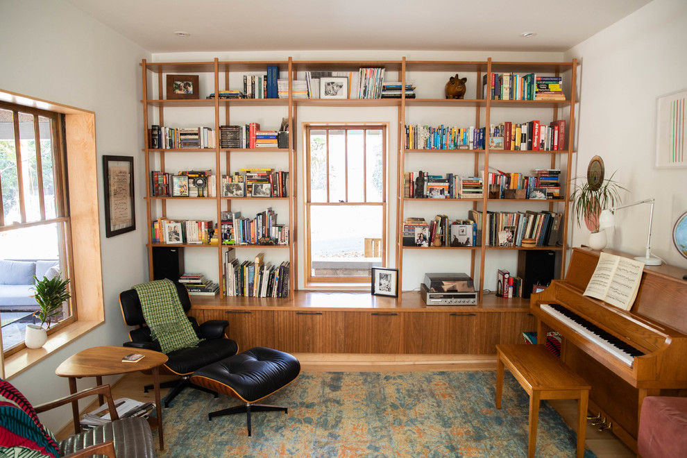 Idéer för ett modernt allrum, med ett bibliotek, vita väggar, mellanmörkt trägolv och brunt golv