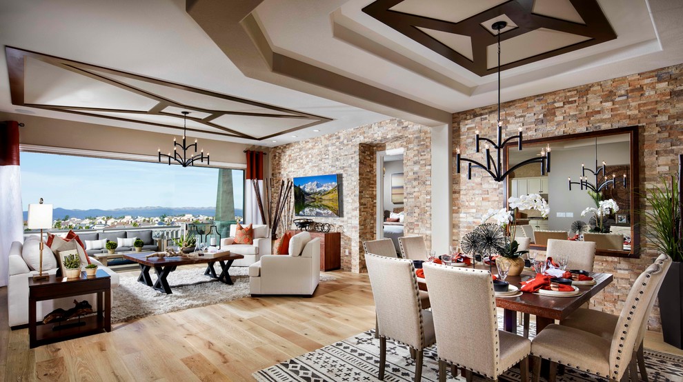 Modelo de sala de estar abierta de estilo americano extra grande con suelo de madera clara y televisor colgado en la pared
