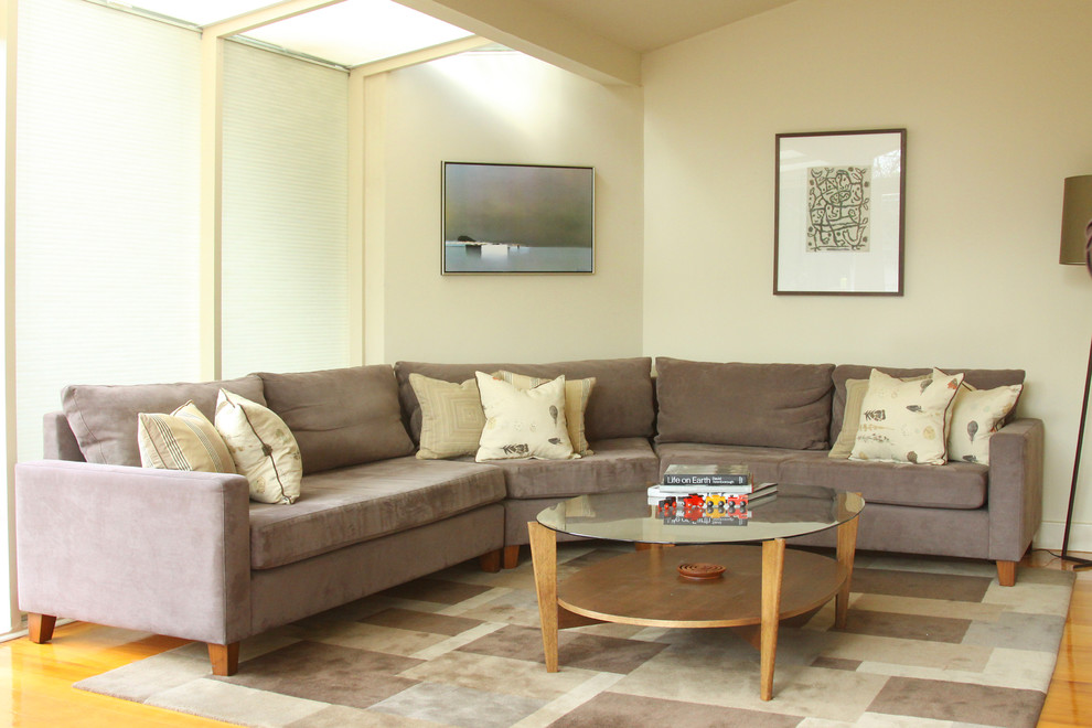Diseño de sala de estar cerrada bohemia de tamaño medio con paredes beige, suelo de madera en tonos medios y televisor colgado en la pared