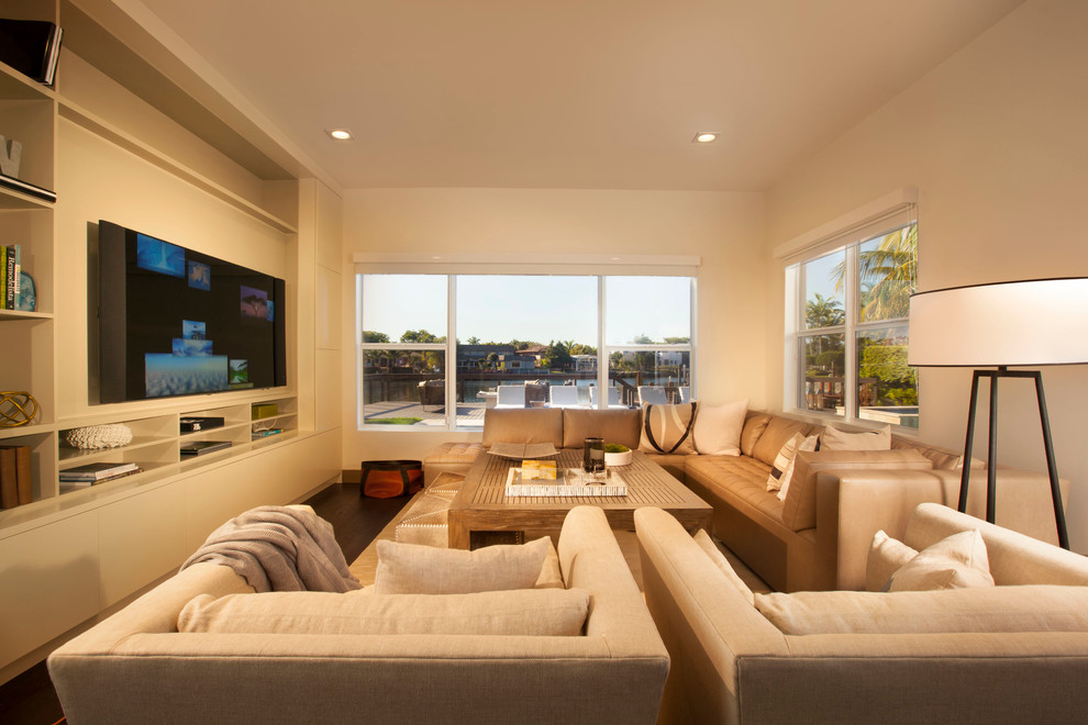 Modernes Wohnzimmer mit beiger Wandfarbe, dunklem Holzboden und Multimediawand in Miami