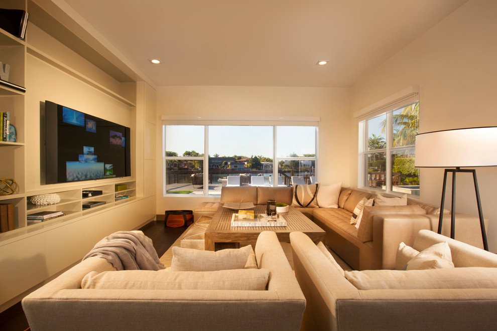 Inspiration for a contemporary dark wood floor family room remodel in Miami with beige walls and a media wall