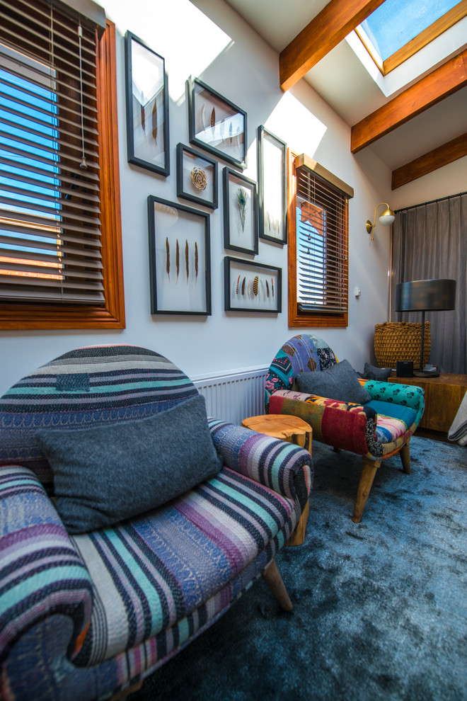 Immagine di un piccolo soggiorno bohémian chiuso con pareti bianche, moquette, nessun camino e pavimento blu