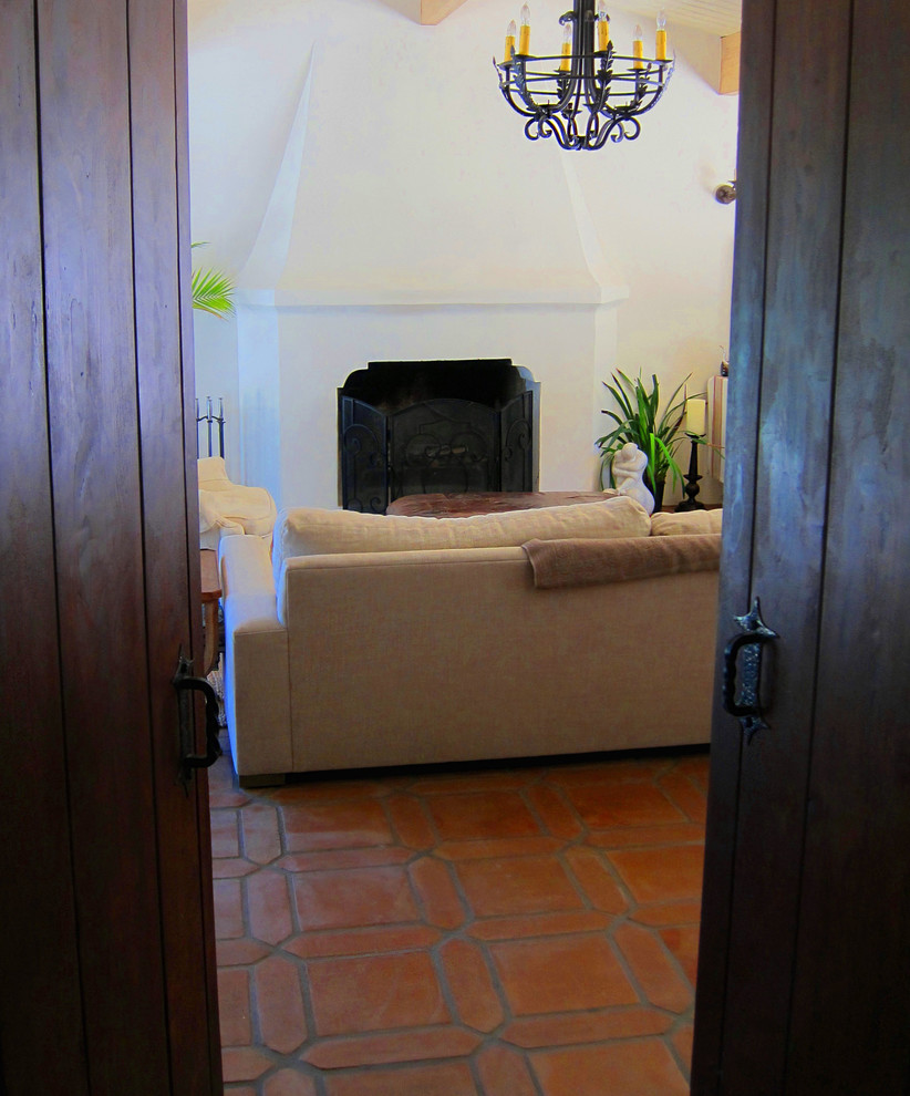 Источник вдохновения для домашнего уюта: маленькая изолированная гостиная комната в средиземноморском стиле с белыми стенами, полом из терракотовой плитки, стандартным камином, фасадом камина из бетона и красным полом для на участке и в саду