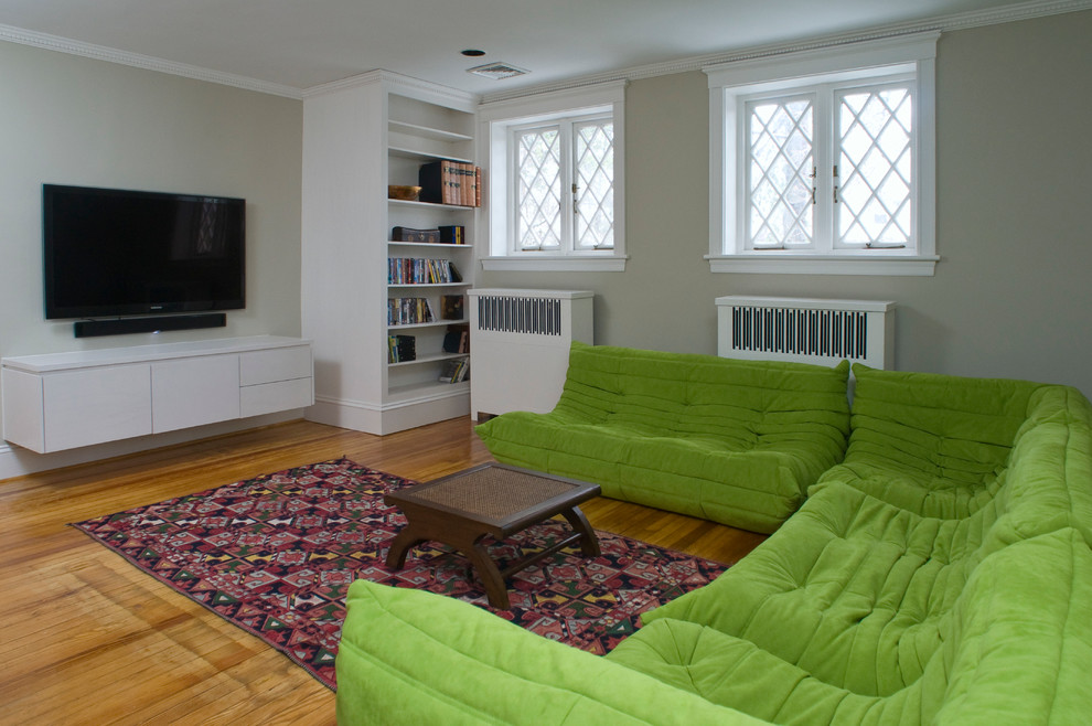 Cette image montre une salle de séjour design fermée et de taille moyenne avec un mur beige, un sol en bois brun, un téléviseur fixé au mur et aucune cheminée.