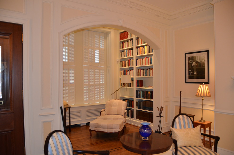 Diseño de sala de estar con biblioteca cerrada clásica pequeña con paredes amarillas y suelo de madera en tonos medios