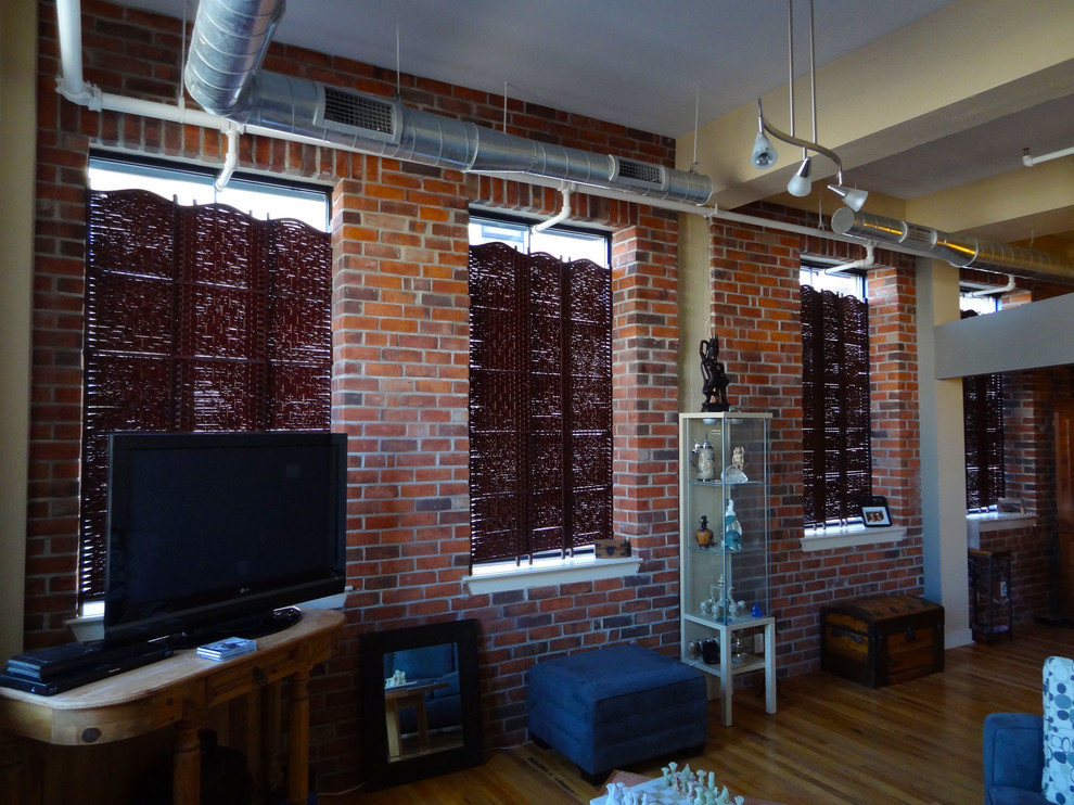 Cette image montre une grande salle de séjour urbaine ouverte avec un mur beige, un sol en bois brun et un téléviseur indépendant.