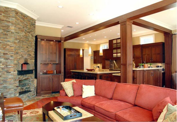 Foto de sala de estar abierta clásica renovada grande sin televisor con paredes beige, suelo de madera en tonos medios, chimenea de esquina y marco de chimenea de piedra