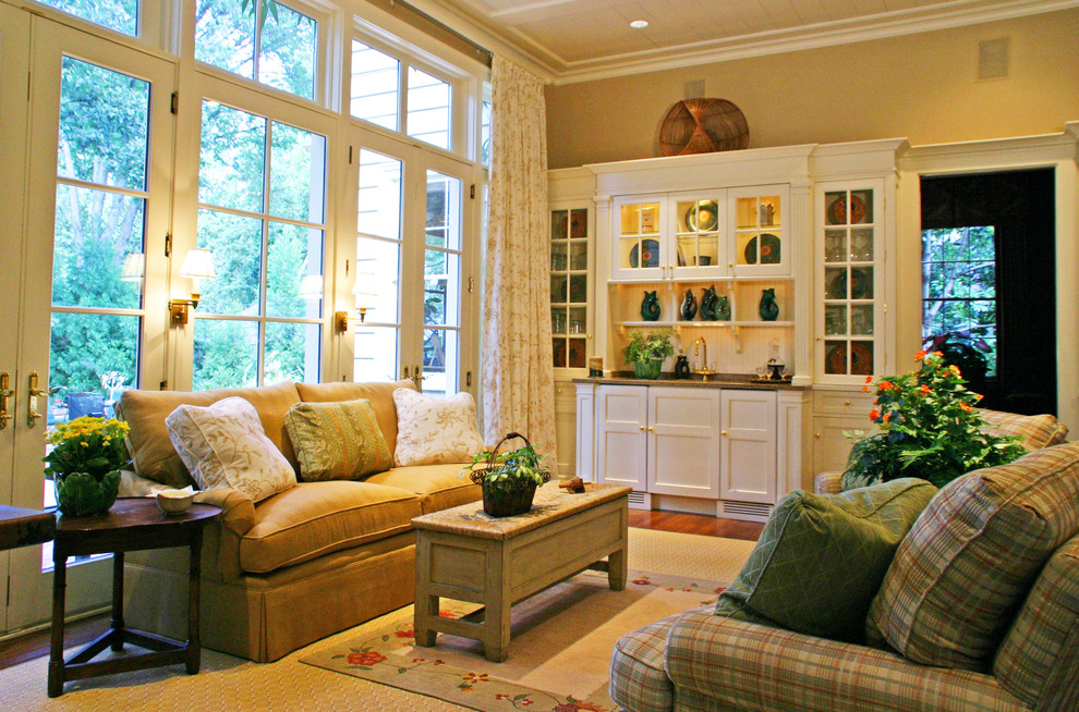 Diseño de sala de estar con barra de bar cerrada tradicional de tamaño medio sin chimenea y televisor con paredes beige, suelo de madera en tonos medios y suelo marrón