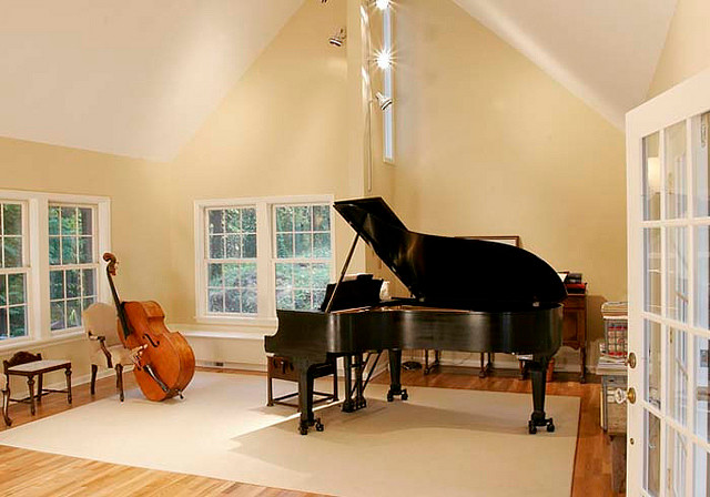 Imagen de sala de estar con rincón musical cerrada tradicional de tamaño medio sin chimenea con paredes beige y suelo de madera en tonos medios