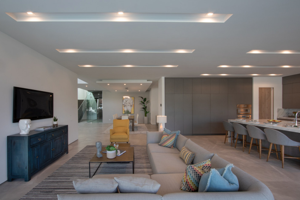 Immagine di un ampio soggiorno minimalista aperto con pareti bianche, TV a parete e pavimento beige