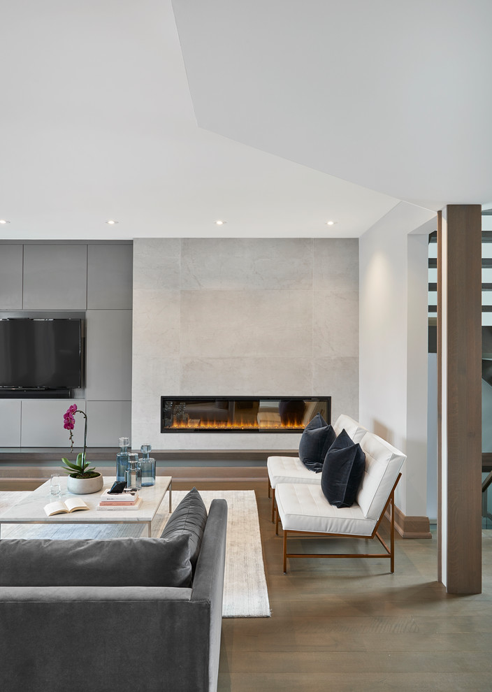 Cette photo montre une grande salle de séjour moderne ouverte avec un mur blanc, parquet clair, un manteau de cheminée en carrelage, un téléviseur encastré, une cheminée ribbon et un sol marron.