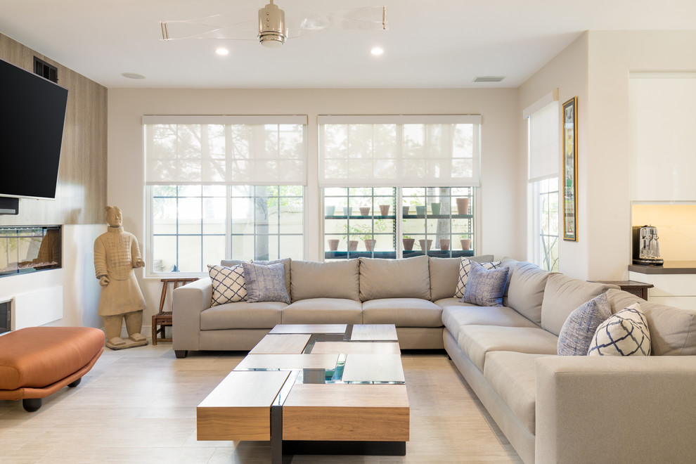 Ejemplo de sala de estar abierta contemporánea de tamaño medio con chimenea lineal, televisor colgado en la pared, paredes beige y suelo beige