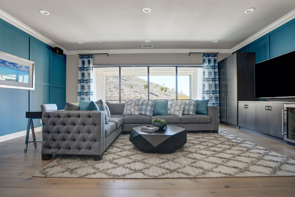 Diseño de sala de estar tradicional renovada con paredes azules, suelo de madera en tonos medios, televisor colgado en la pared y suelo marrón