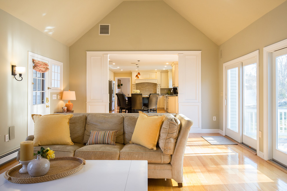 Diseño de sala de estar clásica renovada grande con paredes beige, todas las chimeneas, marco de chimenea de ladrillo, televisor en una esquina y suelo de madera clara