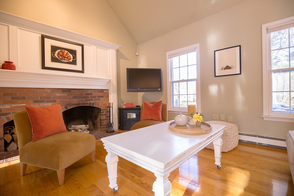 Large traditional games room in Boston with beige walls, a standard fireplace, a brick fireplace surround, a corner tv and light hardwood flooring.