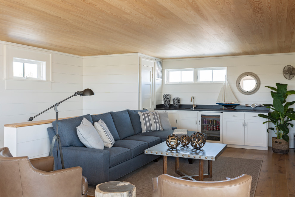 Diseño de sala de estar con barra de bar tipo loft costera sin chimenea con paredes blancas, suelo de madera en tonos medios y alfombra