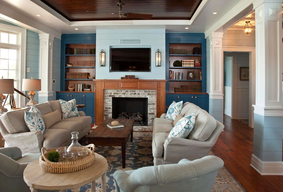 This is an example of a small classic open plan games room in Charleston with medium hardwood flooring, a standard fireplace, a brick fireplace surround, a wall mounted tv, blue walls and brown floors.