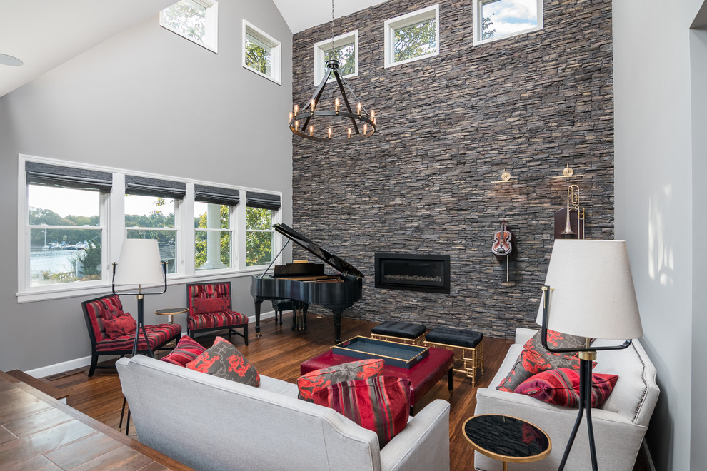Imagen de sala de estar con rincón musical actual con paredes grises, suelo de madera oscura, chimenea lineal y marco de chimenea de piedra