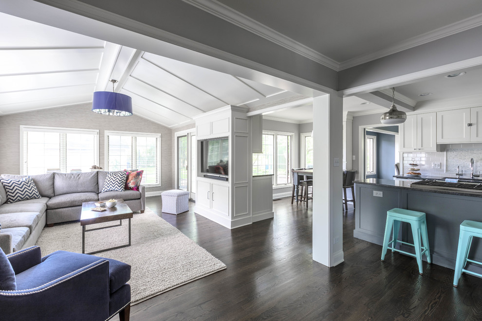 Ejemplo de sala de estar abierta clásica renovada de tamaño medio con paredes beige, suelo de madera oscura y pared multimedia