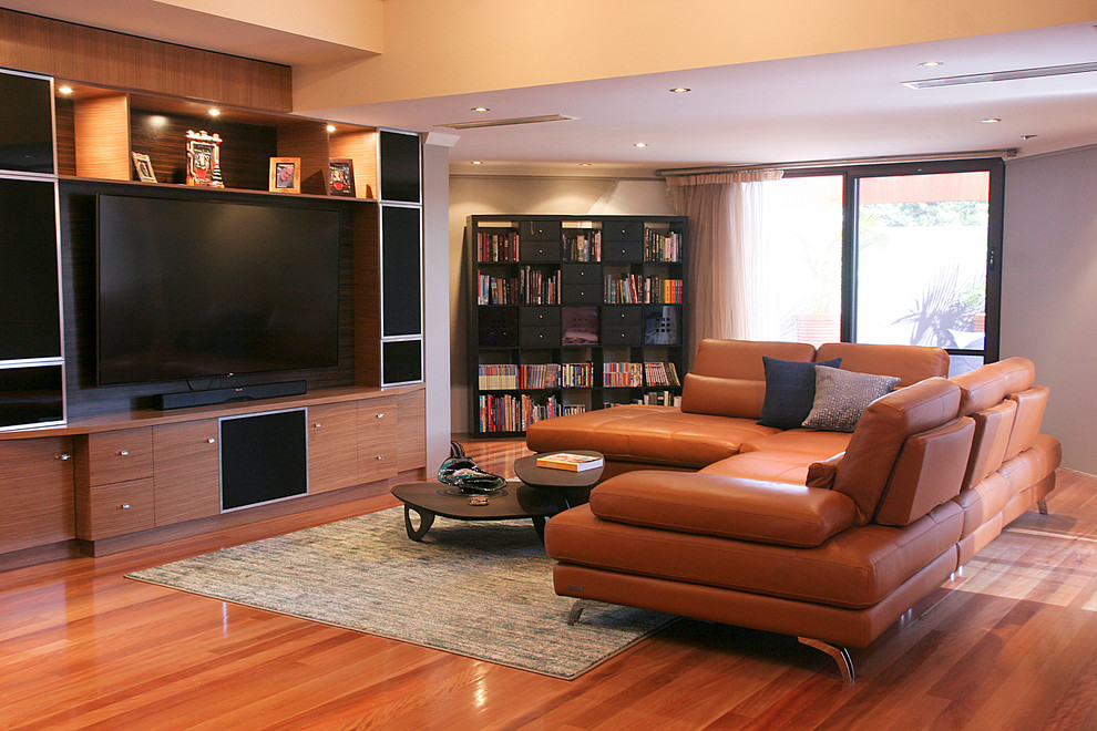 Diseño de sala de estar abierta minimalista grande sin chimenea con paredes beige, suelo de madera en tonos medios, pared multimedia y suelo rojo