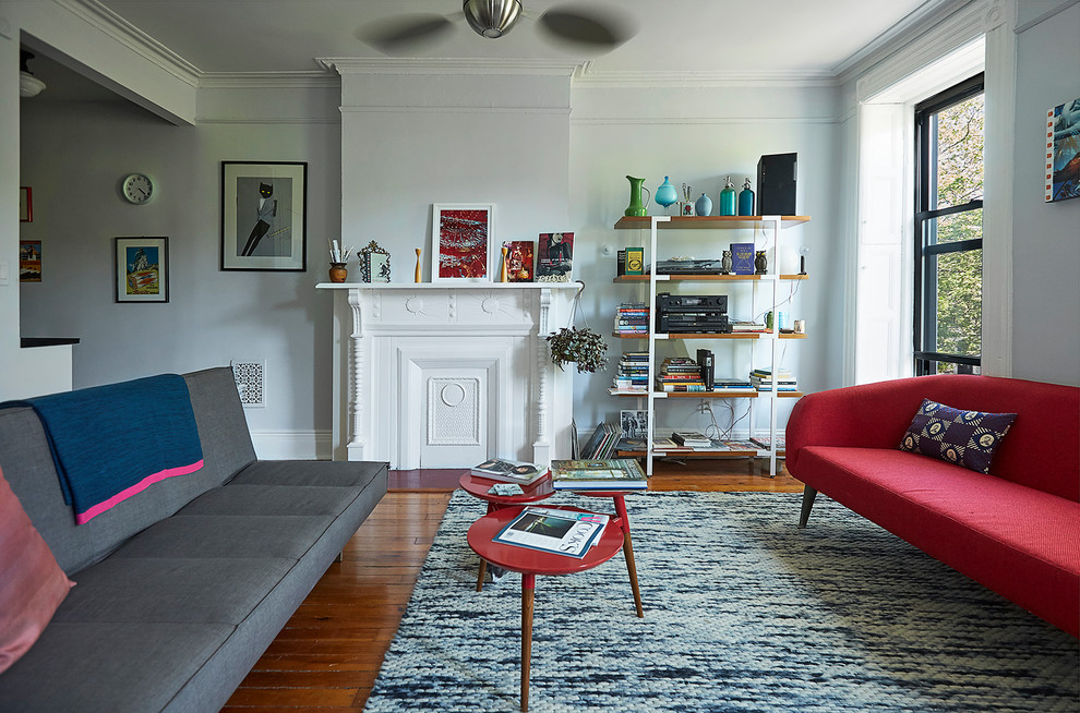 Diseño de sala de estar ecléctica con paredes grises, suelo de madera en tonos medios y todas las chimeneas